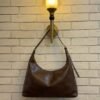 Chocolate Brown hobo shoulder bag with a tonal strap against a brick wall