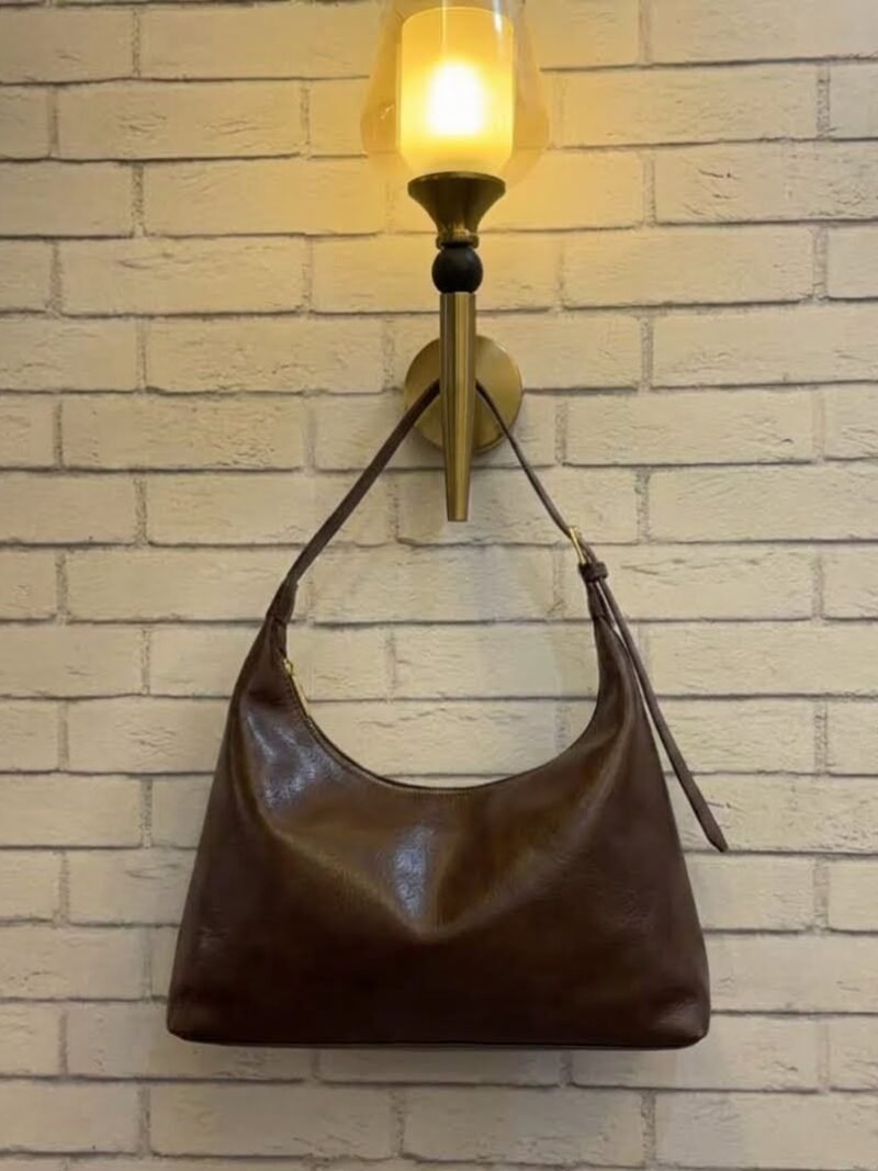 Chocolate Brown hobo shoulder bag with a tonal strap against a brick wall