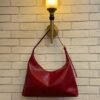 Cherry Red hobo shoulder bag with a tonal strap against a brick wall