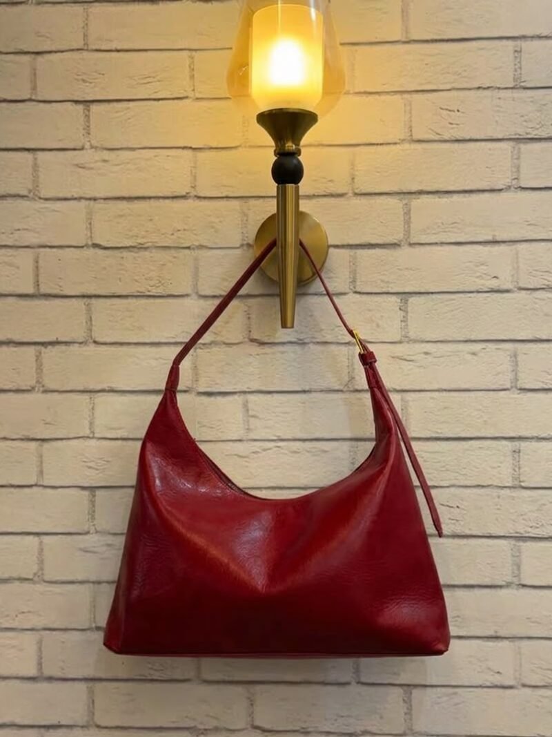 Cherry Red hobo shoulder bag with a tonal strap against a brick wall
