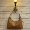 Caramel Tan hobo shoulder bag with a tonal strap against a brick wall